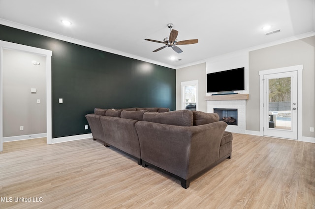 living room with ornamental molding, light hardwood / wood-style floors, and ceiling fan