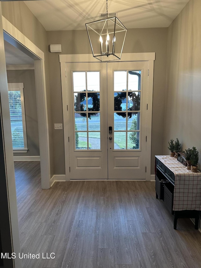 doorway to outside with dark hardwood / wood-style flooring, a notable chandelier, and french doors