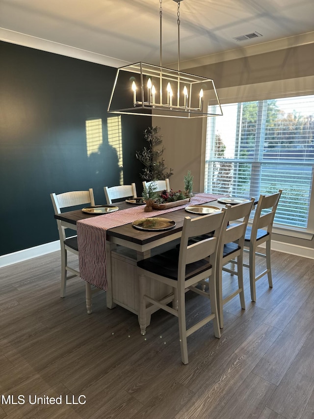 dining area with crown molding and dark wood-type flooring