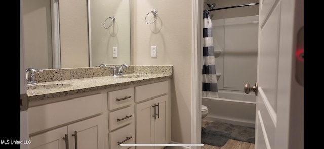 full bathroom with hardwood / wood-style floors, vanity, shower / tub combo with curtain, and toilet