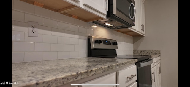 kitchen with light stone countertops, white cabinetry, appliances with stainless steel finishes, and tasteful backsplash