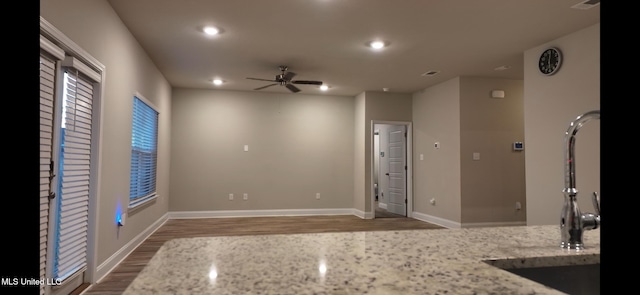 kitchen with light stone countertops, dark hardwood / wood-style flooring, and ceiling fan