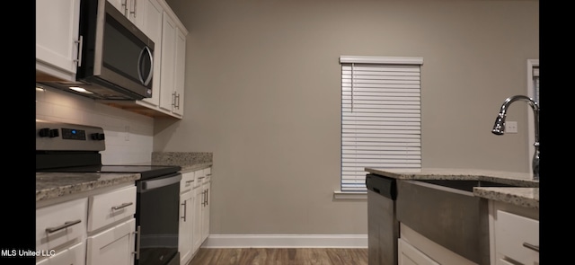 kitchen featuring white cabinetry, sink, stainless steel appliances, light stone counters, and dark hardwood / wood-style flooring