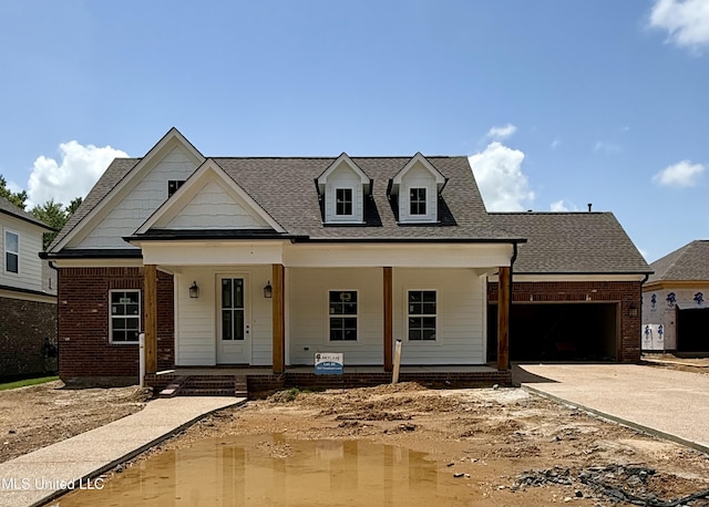 1347 Creekside Ln, Hernando, MS 38632 - view of front of home with an attached garage, brick siding, driveway, covered porch, and a shingled roof