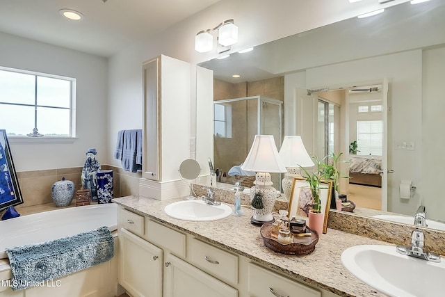 full bath with a stall shower, double vanity, a sink, and ensuite bathroom