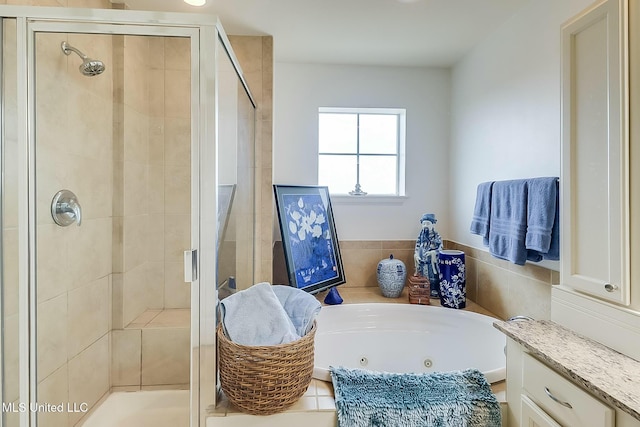 bathroom with a stall shower, a jetted tub, and vanity