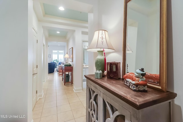 corridor with recessed lighting, a raised ceiling, baseboards, and light tile patterned floors