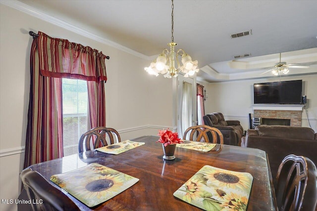 2120 Meagan Dr, Byram, MS 39272 - dining space featuring ornamental molding, a chandelier, a stone fireplace, a ceiling fan, and a tray ceiling