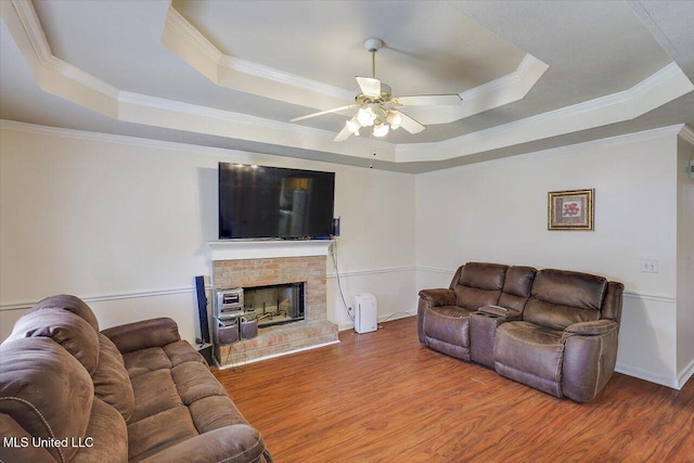 2120 Meagan Dr, Byram, MS 39272 - living room featuring a tray ceiling, wood finished floors, ceiling fan, ornamental molding, and a brick fireplace