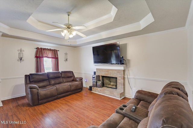 2120 Meagan Dr, Byram, MS 39272 - living room with a tray ceiling, a ceiling fan, wood finished floors, a fireplace, and crown molding