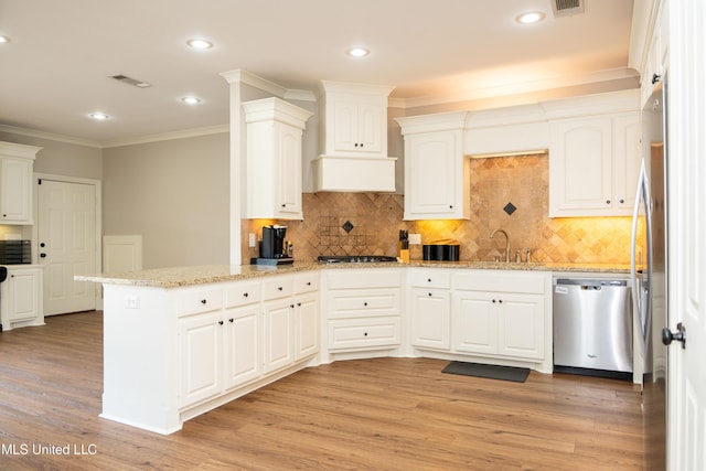 105 Bridgeton Way, Canton, MS 39046 - kitchen with appliances with stainless steel finishes, a peninsula, ornamental molding, light wood-style flooring, and backsplash