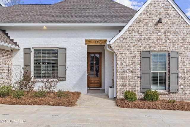 property entrance with brick siding and roof with shingles