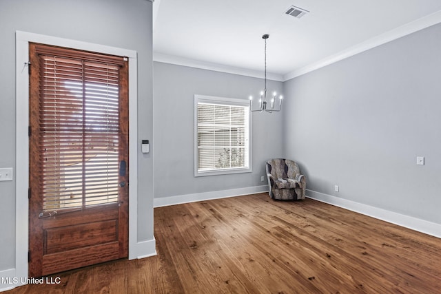 interior space featuring baseboards, visible vents, wood finished floors, an inviting chandelier, and crown molding