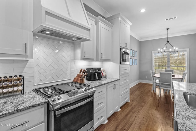 kitchen with stainless steel appliances, premium range hood, white cabinetry, visible vents, and crown molding