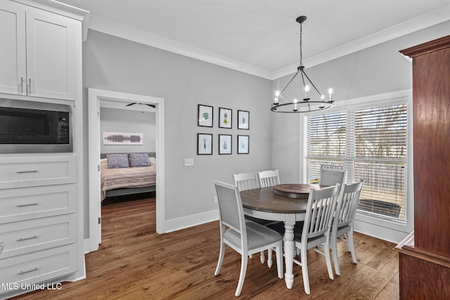 dining area featuring dark wood-style floors, baseboards, a notable chandelier, and crown molding