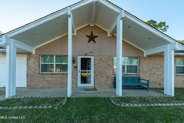 view of exterior entry with a garage and brick siding