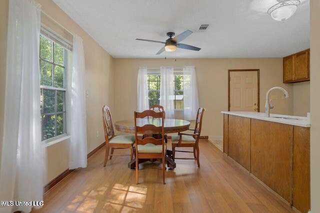 dining space featuring visible vents, ceiling fan, light wood-style flooring, and baseboards