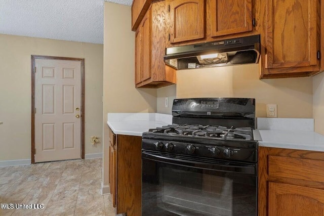 kitchen featuring black gas range, under cabinet range hood, brown cabinets, and light countertops