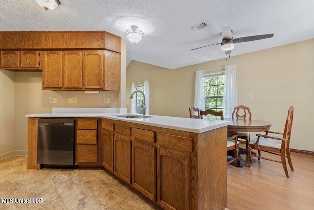 kitchen featuring visible vents, dishwasher, brown cabinets, light countertops, and a sink