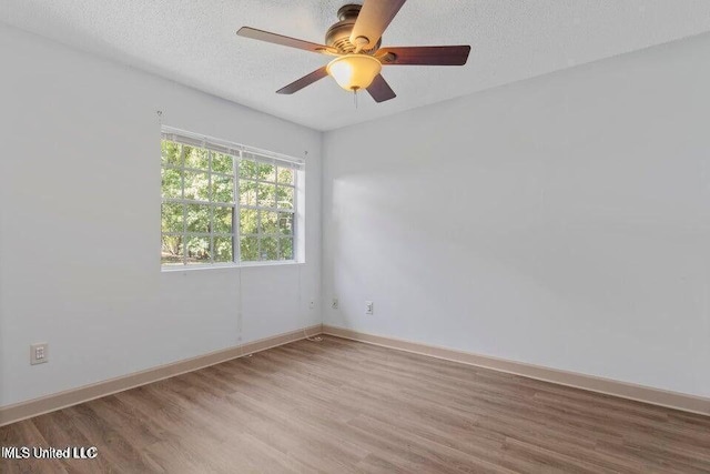 spare room with ceiling fan, a textured ceiling, baseboards, and wood finished floors