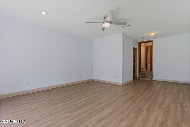 spare room with light wood-type flooring, baseboards, visible vents, and ceiling fan