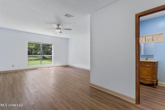 unfurnished room with visible vents, a textured ceiling, baseboards, and wood finished floors