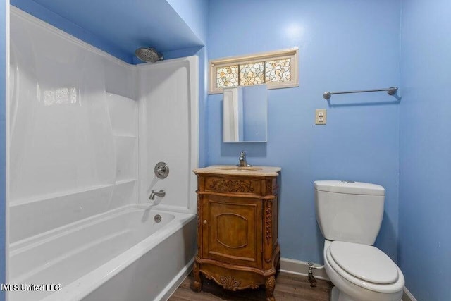 full bathroom featuring baseboards, toilet, wood finished floors, vanity, and washtub / shower combination