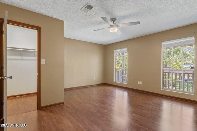 unfurnished bedroom with baseboards, a textured ceiling, visible vents, and wood finished floors