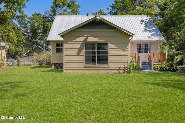 rear view of property featuring a deck, metal roof, and a lawn