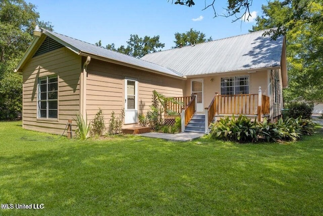 rear view of property featuring metal roof, a lawn, and a wooden deck