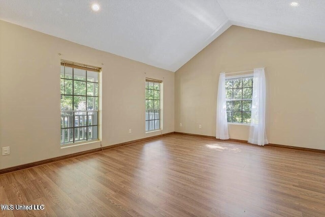 unfurnished room with lofted ceiling, wood finished floors, and baseboards