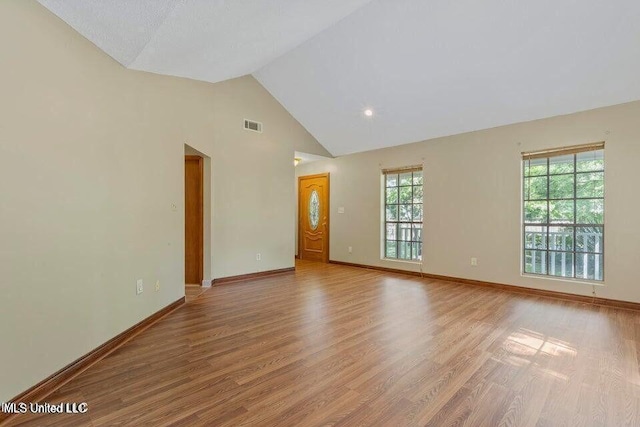 unfurnished room with high vaulted ceiling, light wood finished floors, visible vents, and baseboards