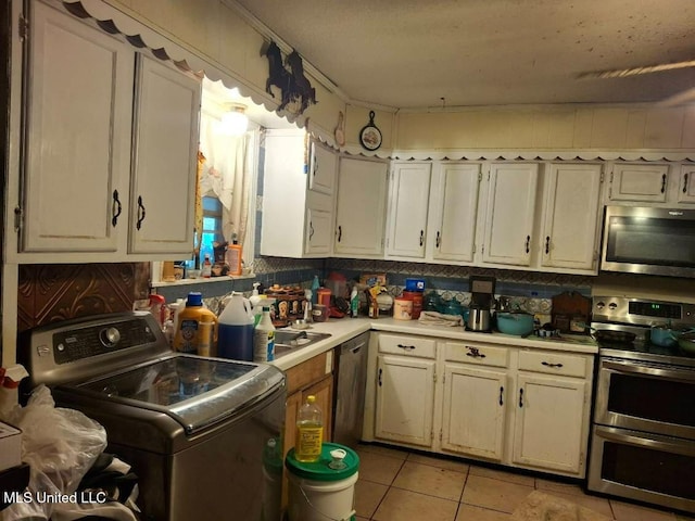 kitchen featuring washer / dryer, light tile patterned flooring, light countertops, and appliances with stainless steel finishes