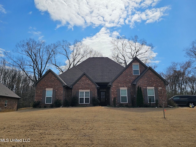 view of front of house featuring brick siding, a front yard, and a shingled roof