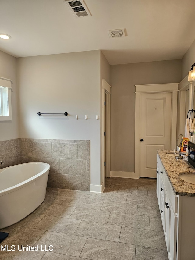 full bathroom featuring a freestanding tub, visible vents, and vanity