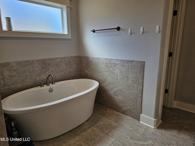 bathroom with a soaking tub and tile walls