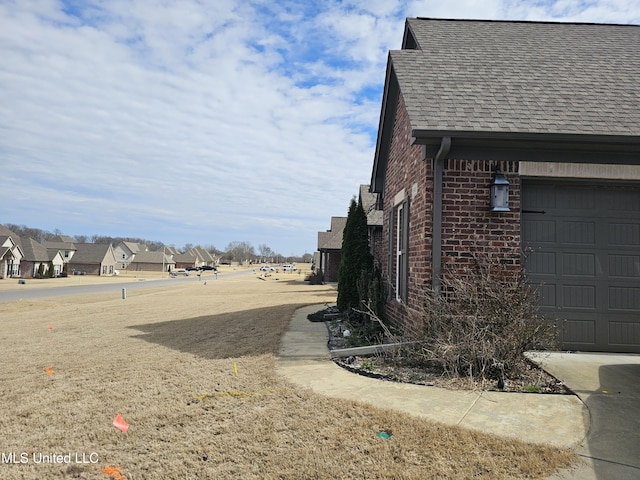 view of property exterior with a garage, roof with shingles, a residential view, and brick siding