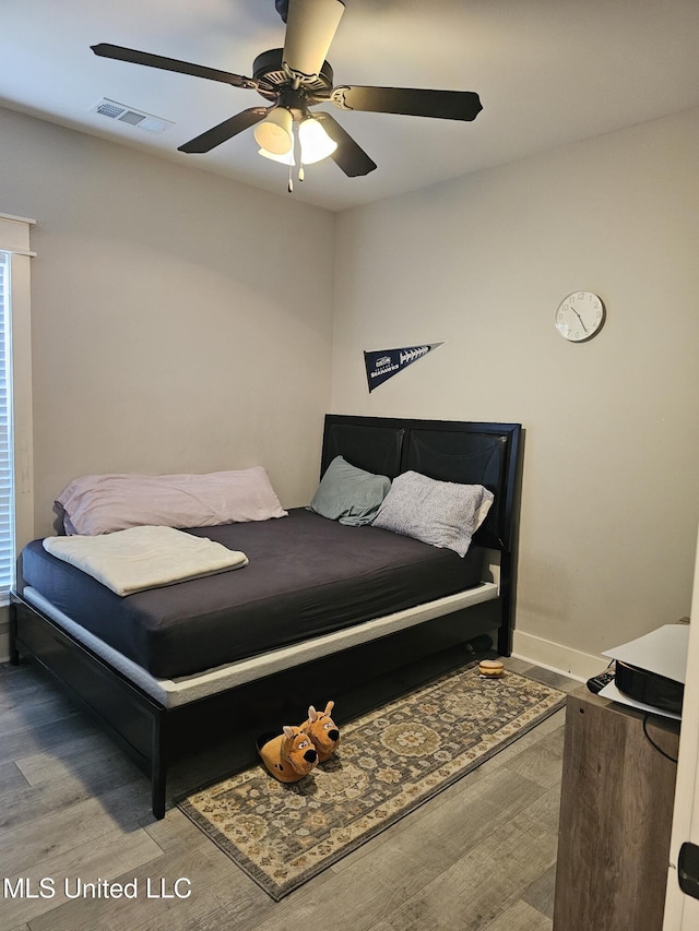 bedroom with baseboards, wood finished floors, visible vents, and a ceiling fan