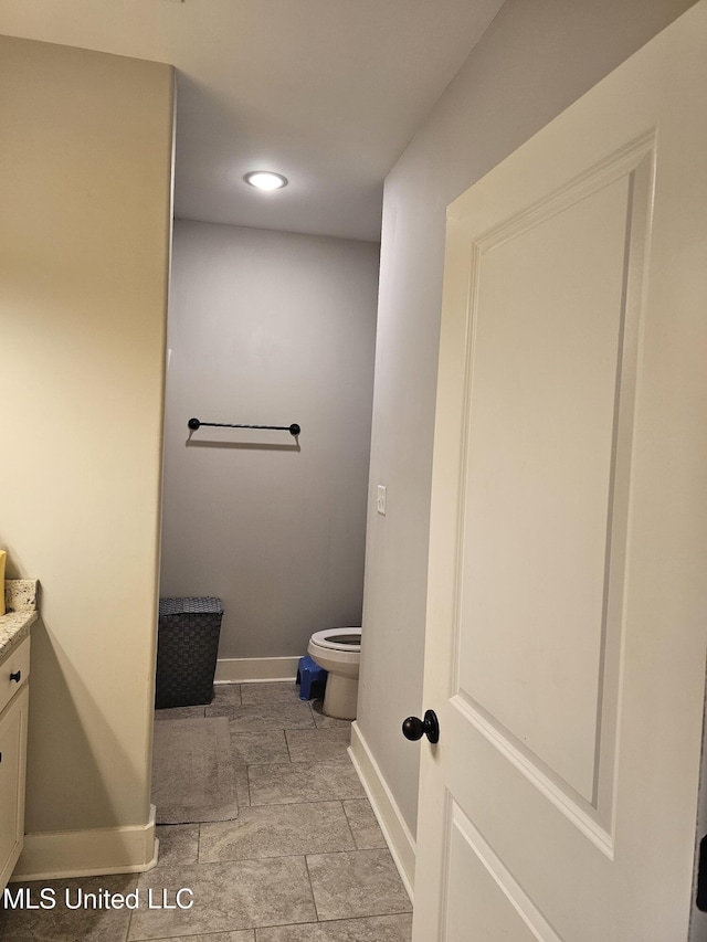 bathroom with vanity, toilet, and baseboards