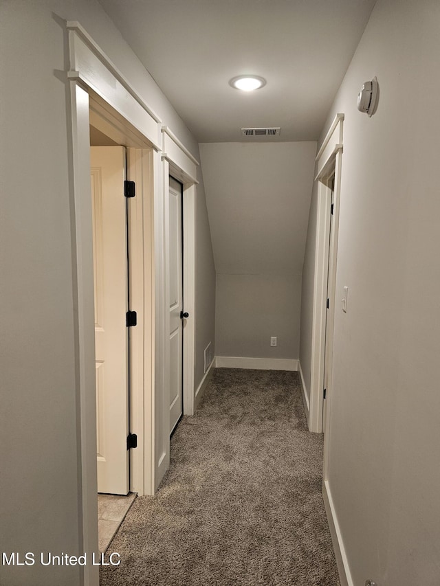 hall featuring vaulted ceiling, carpet flooring, visible vents, and baseboards