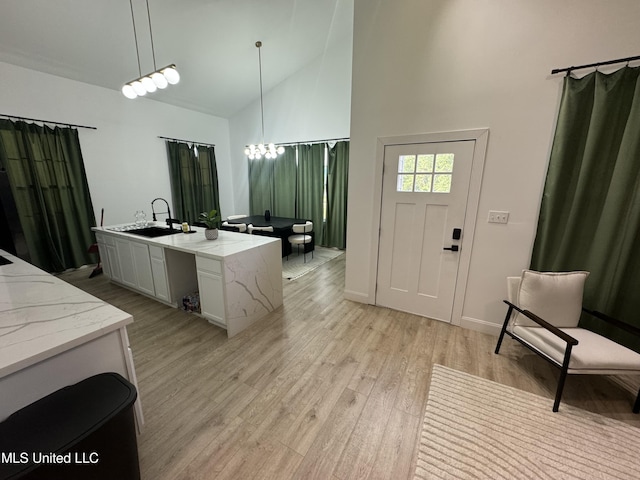 interior space featuring vanity, hardwood / wood-style flooring, high vaulted ceiling, and a notable chandelier