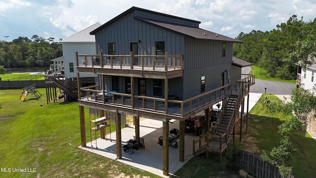 back of property with a deck, a patio, and a yard