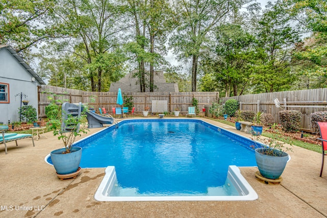 view of swimming pool featuring a water slide and a patio area