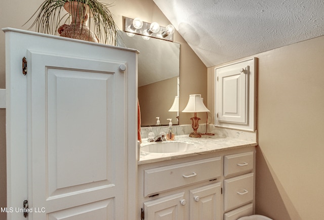 bathroom featuring vanity, a textured ceiling, and vaulted ceiling