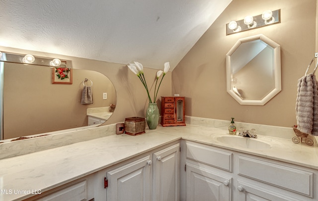 bathroom with vanity, a textured ceiling, and vaulted ceiling