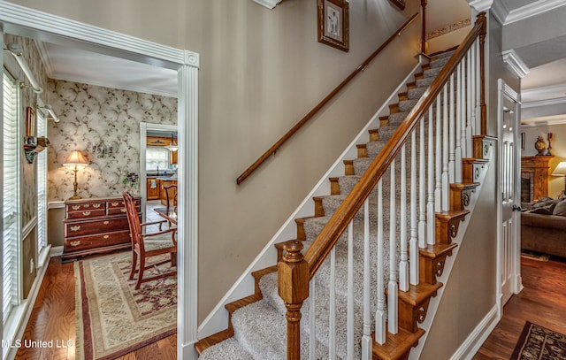 stairway with a healthy amount of sunlight, hardwood / wood-style flooring, and crown molding