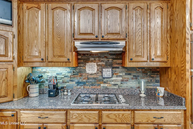 kitchen with dark stone countertops, backsplash, and stainless steel gas cooktop