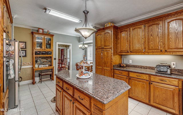 kitchen featuring ornamental molding, stainless steel refrigerator, hanging light fixtures, a chandelier, and a center island