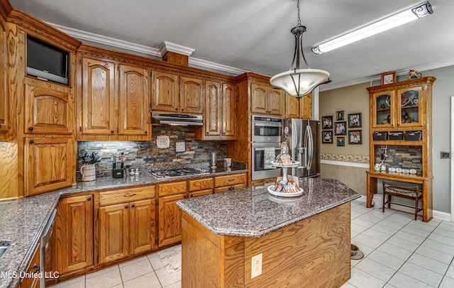 kitchen with dark stone counters, ornamental molding, appliances with stainless steel finishes, and a center island