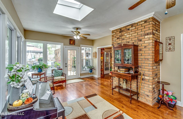 living room featuring wood-type flooring, ceiling fan, and a skylight